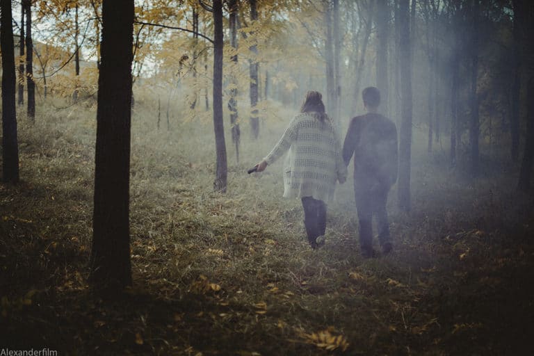 couple walking through foggy forest holding hands