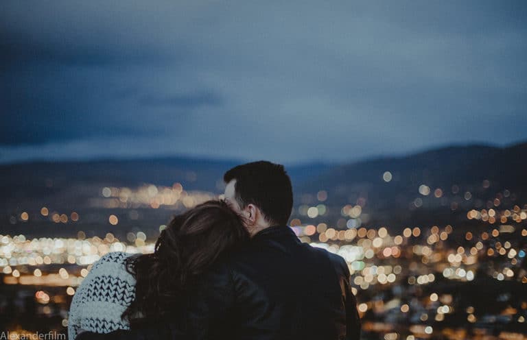 couple cuddling and looking towards city