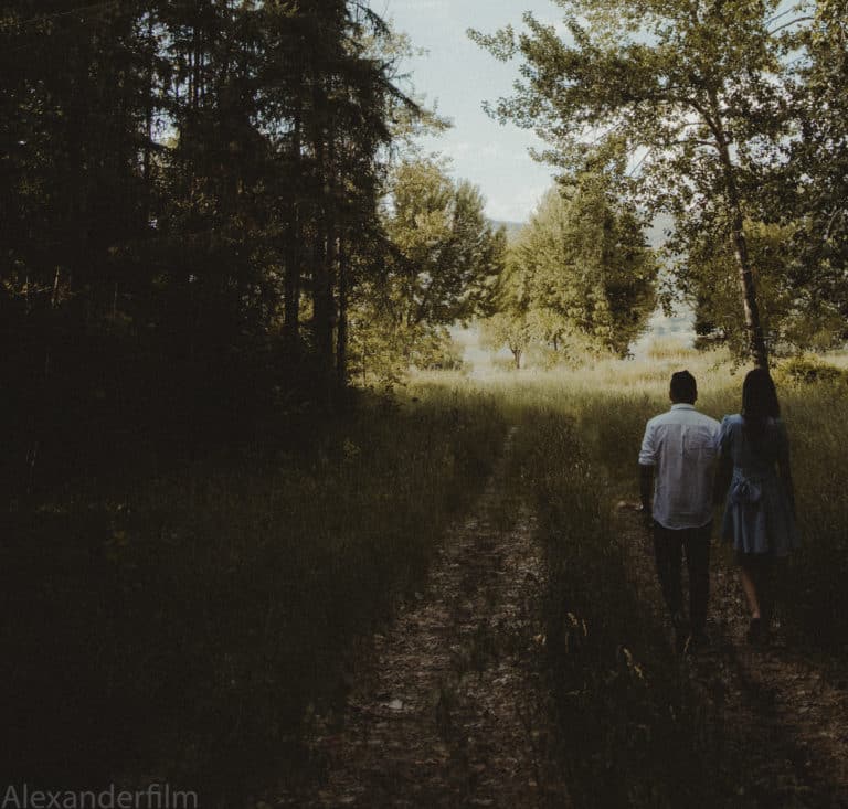 couple walking down field into forest