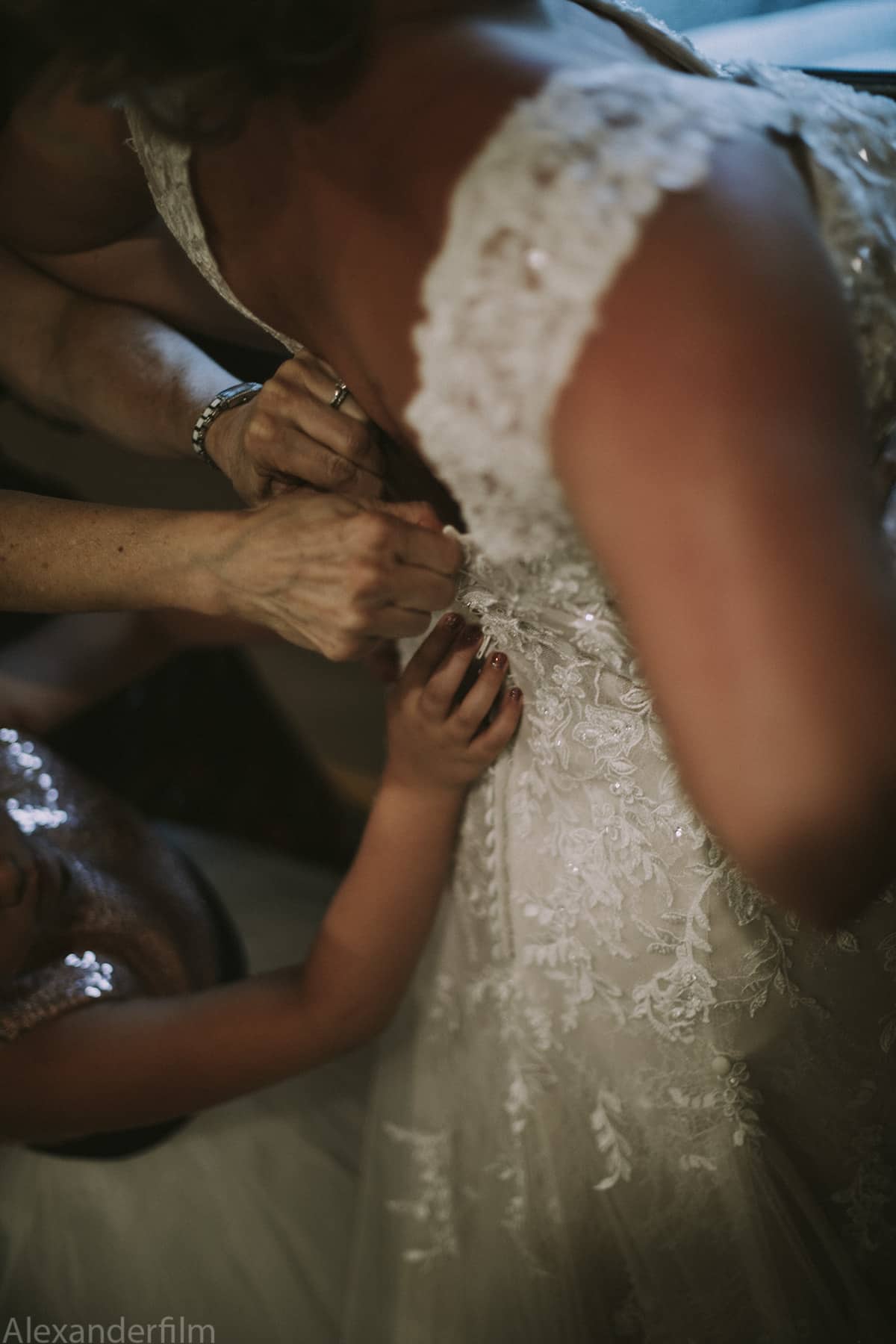 a wedding dress being buttoned from behind