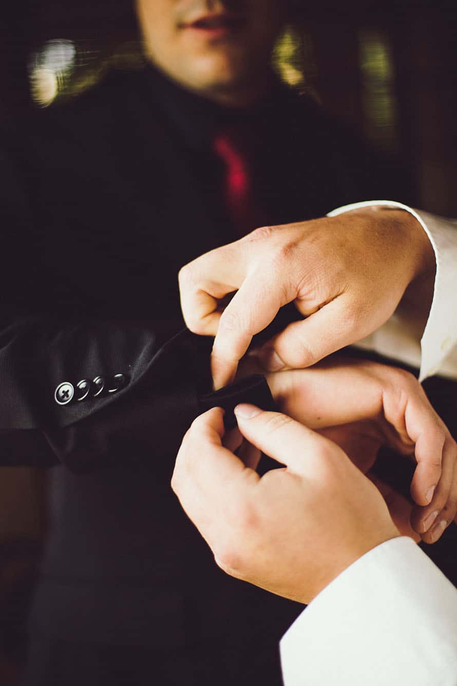 a man helping another with a cufflink