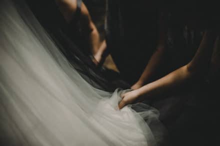 woman holding back of brides dress