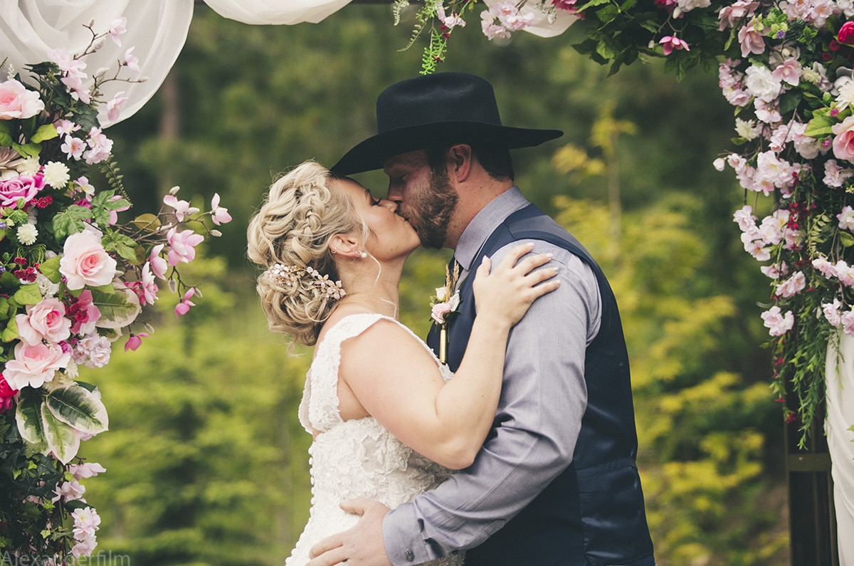 a cowboy and a bride kissing