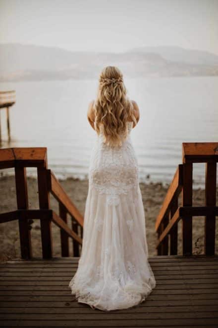Woman looking off to the lake wearing wearing a wedding dress
