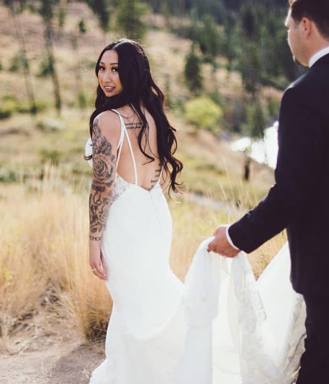 a groom holding up a woman's wedding dress