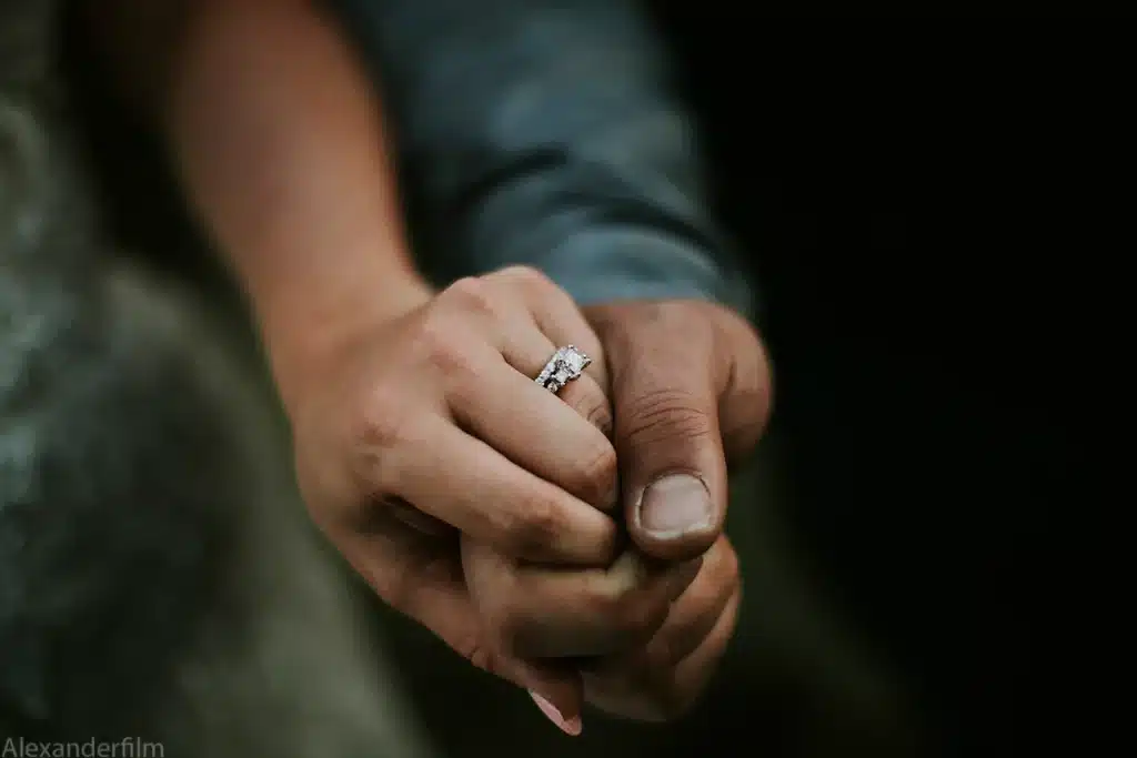 man holding woman's hand, new wedding ring on her finger