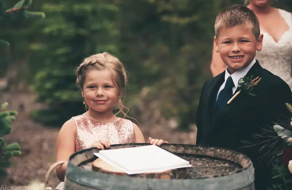 young boy and girl standing around a barrel nicely dressed looking at camera
