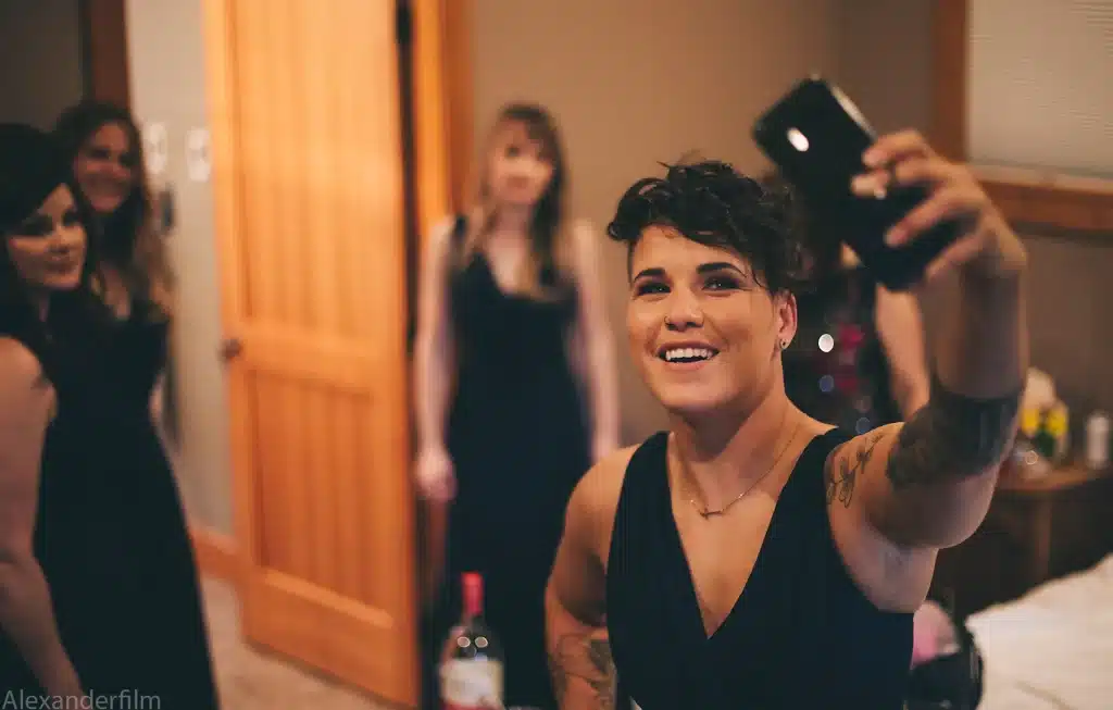 woman taking selfie with bridal party behind her
