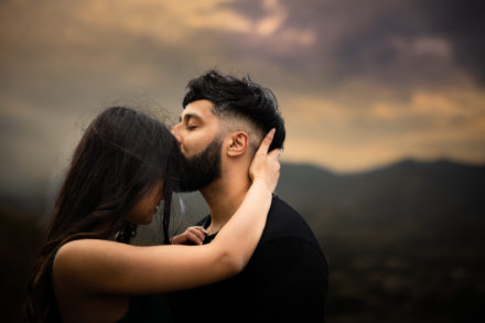 man kissing woman for-head