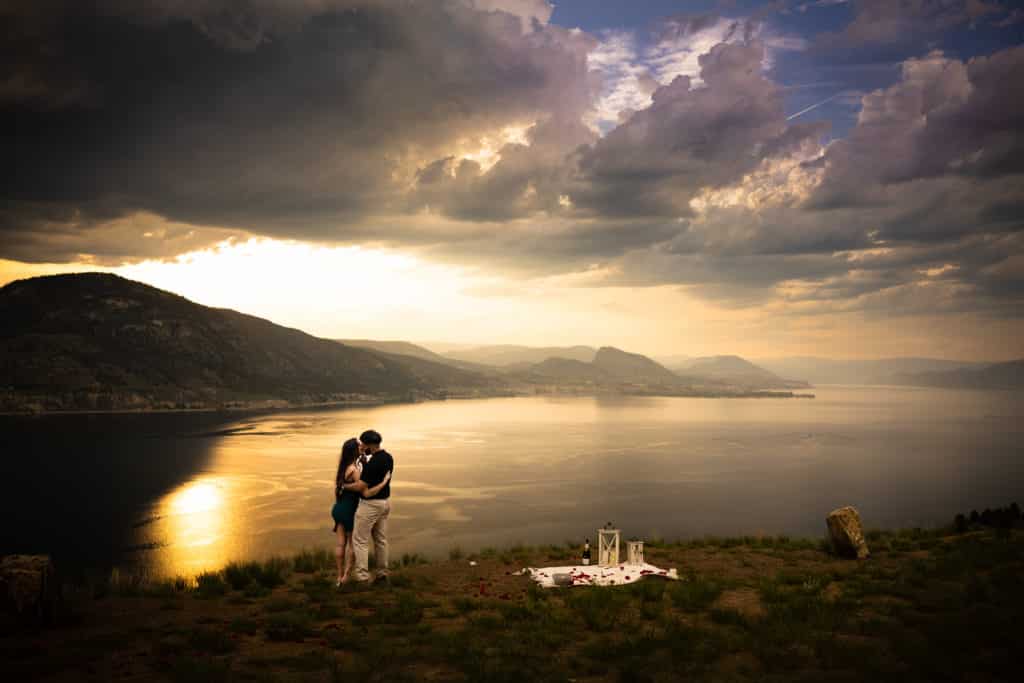 couple looking out towards lake hugging sunset
